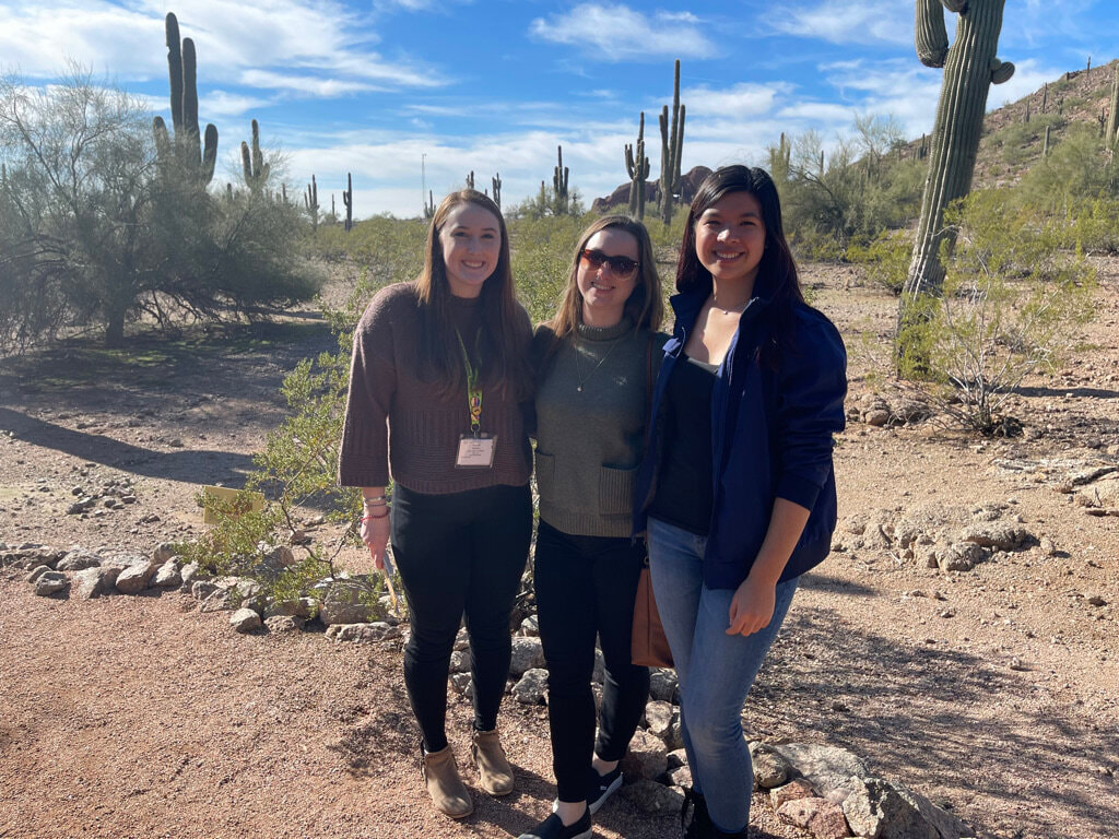Hannah, Valerie, and Adrienne standing with cacti. 